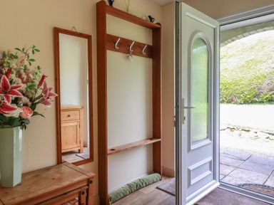 A hallway with a coat rack and mirror at Underlanes in Boscastle