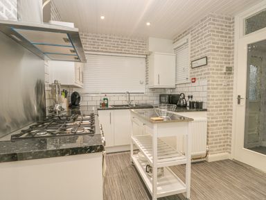 A kitchen with a gas stove oven, white cabinets, a kitchen island, and brick patterned walls at Hillcrest in Scarborough