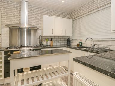 A kitchen with white cabinets black countertops a stainless steel stove and a kitchen island at Hillcrest in Scarborough