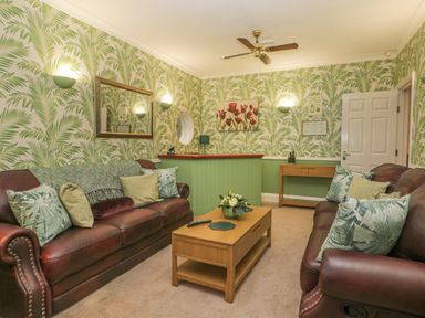 A living room with two leather sofas wooden coffee table and green leaf wallpaper at Hillcrest in Scarborough
