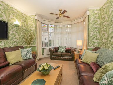 A living room with brown leather sofas green cushions wooden coffee table and tropical wallpaper at Hillcrest in Scarborough