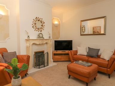 A living room with a fireplace a TV on a stand leather sofas and a plant on a table at Hillcrest in Scarborough