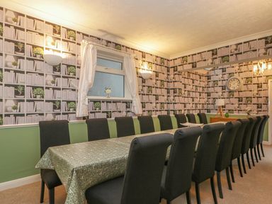 A dining room with a long table covered with a tablecloth and black chairs around it at Hillcrest in Scarborough