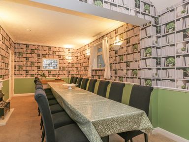 A dining room with a long table covered with a tablecloth and black chairs along the sides at Hillcrest in Scarborough