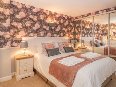 A bedroom with a double bed two bedside tables with lamps and mirrored wardrobes at Hillcrest in Scarborough