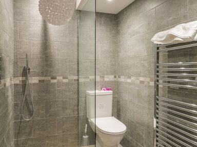 A bathroom with a toilet shower area and chrome towel radiator at Hillcrest in Scarborough