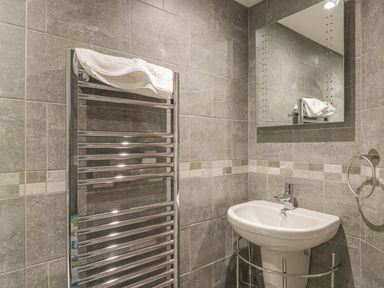 A bathroom with a pedestal sink a chrome towel rack with a white towel and a wall mirror at Hillcrest in Scarborough