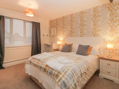 A bedroom with a double bed two bedside tables with lamps a window with blinds and curtains and a sink at Hillcrest in Scarborough
