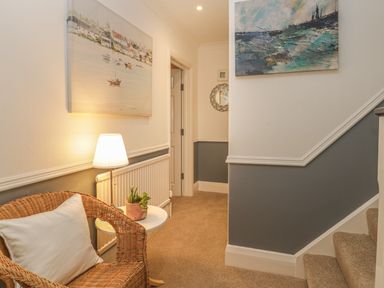 A hallway with a wicker chair pillow lamp and a small table with plants at Hillcrest in Scarborough