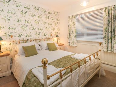A bedroom with a double bed two bedside tables with lamps floral wallpaper and curtains at Hillcrest in Scarborough