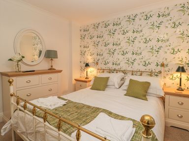 A bedroom with a bed with green pillows and white bedding a dresser with a mirror and lamps at Hillcrest in Scarborough