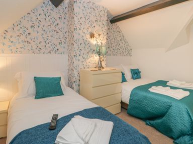 A bedroom with two single beds a dresser and floral wallpaper at Hillcrest in Scarborough