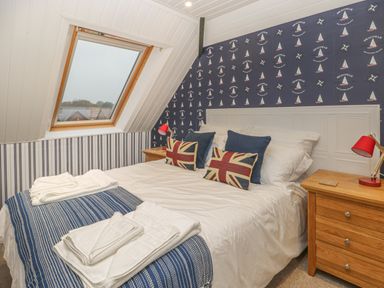A bedroom with a bed with pillows and towels beside a window and wooden bedside tables at Hillcrest in Scarborough