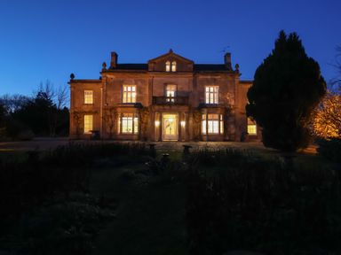 A house with illuminated windows and a garden at Milton Manor in Milton On Stour