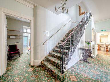 A hallway featuring a staircase and a chair at Milton Manor in Milton On Stour