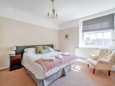 A bedroom with a bed and a chair at Milton Manor in Milton On Stour