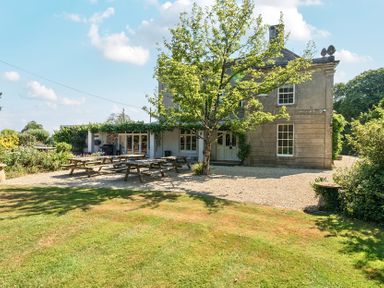 A house with picnic tables and a tree in the garden at Milton Manor in Milton On Stour