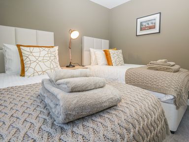 A bedroom with two single beds with headboards bedside lamp folded towels and a framed picture on the wall at Bishop Fell in Newby Bridge
