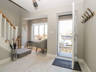 An entryway with an open door a chair umbrella stand and stairs at Bishop Fell in Newby Bridge