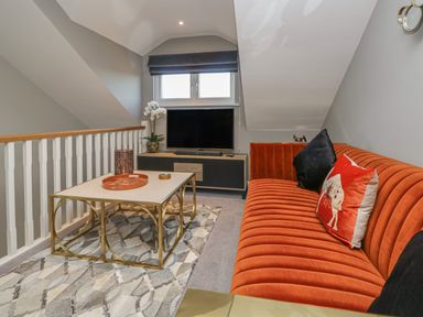 A living room with an orange sofa a coffee table and a television at Bishop Fell in Newby Bridge