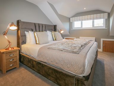 A bedroom with a bed bedside tables lamps and a window at Bishop Fell in Newby Bridge