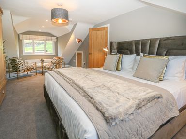A bedroom with a large bed and two patterned chairs by a window at Bishop Fell in Newby Bridge
