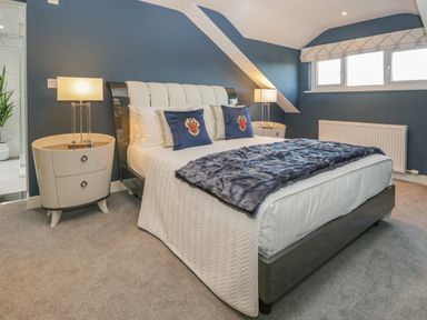 A bedroom with a bed with pillows and blankets two lamps on bedside tables and a window at Bishop Fell in Newby Bridge
