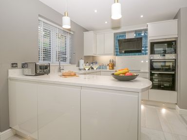 A kitchen with white cabinets a countertop with a toaster bread two glasses and a bowl of fruit at Bishop Fell in Newby Bridge