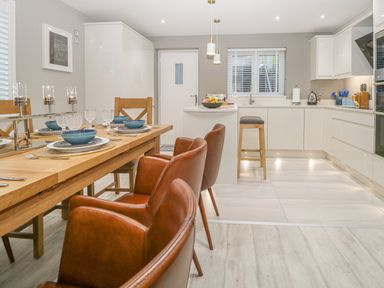 A kitchen and dining area with wooden dining table set and modern white cabinets at Bishop Fell in Newby Bridge