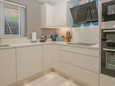 A kitchen with white cabinets a kettle paper towel holder and blue kitchen utensils at Bishop Fell in Newby Bridge