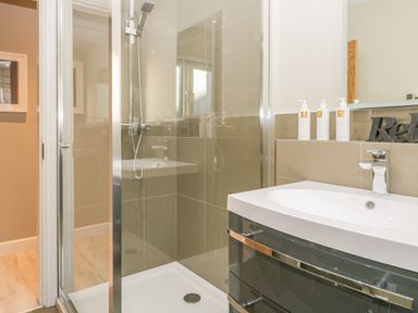 A bathroom with a shower enclosure and a sink with toiletries and a relax sign at Bishop Fell in Newby Bridge