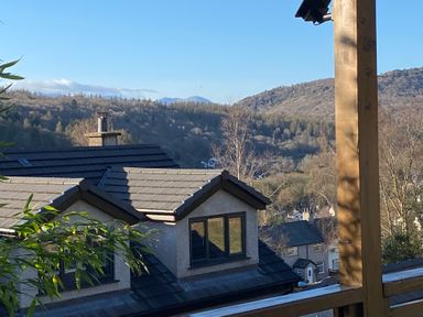 A view of rooftops with hills and trees in the background at Bishop Fell in Newby Bridge