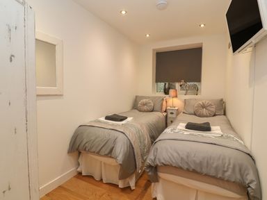 A bedroom with two single beds a bedside table with a lamp and a zebra decor at 1 River View in Looe
