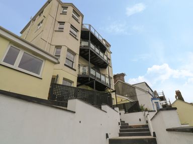 The exterior of a multi-story building with balconies and a staircase leading up at 1 River View in Looe