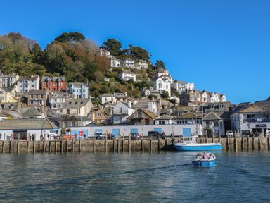 A coastal town with houses on a hillside and boats on the water at 1 River View in Looe