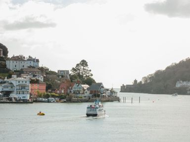 A boat on water near houses and trees at 2 Embankment House in Dartmouth