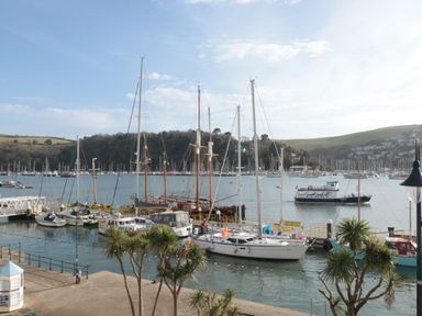 A harbor with several sailboats docked near a walkway with palm trees at 2 Embankment House in Dartmouth