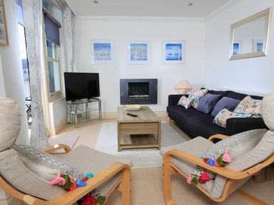 A living room with a sofa and armchairs a coffee table a TV and wall art at 2 Embankment House in Dartmouth