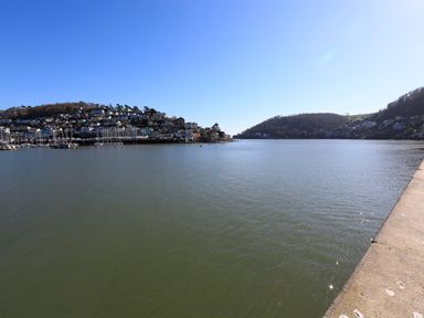 A river with houses on hills and boats docked along the shore at 2 Embankment House in Dartmouth