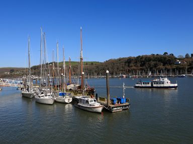 A marina with sailboats and a ferry on the water near wooded hills at 2 Embankment House in Dartmouth