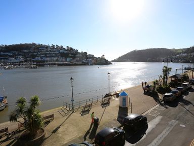 A riverside promenade with benches street lamps and parked cars beside a body of water at 2 Embankment House in Dartmouth