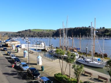 A marina with boats docked along the waterfront and cars parked on the street at 2 Embankment House in Dartmouth