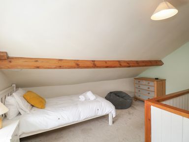 A small bedroom with a single bed a dresser a bean bag and a wooden beam on the ceiling at The Postmasters House in Windermere