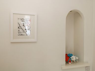 A framed picture on a wall next to a small alcove with two stuffed animals at The Postmasters House in Windermere