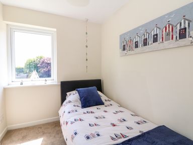 A small bedroom with a single bed near a window and a painting on the wall at Trevore Farmhouse in Chacewater