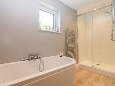 A bathroom with a bathtub shower glass enclosure and heated towel rack at Trevore Farmhouse in Chacewater