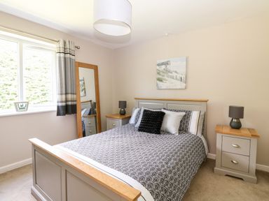 A bedroom with a bed bedside tables lamps and a floor mirror at Trevore Farmhouse in Chacewater