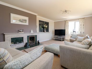 A living room with sofas a fireplace a television and a window at Trevore Farmhouse in Chacewater