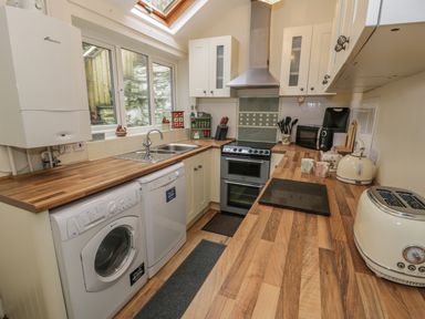 A kitchen with washing machine dishwasher stove toaster and kettle at Manod View in Blaenau Ffestiniog