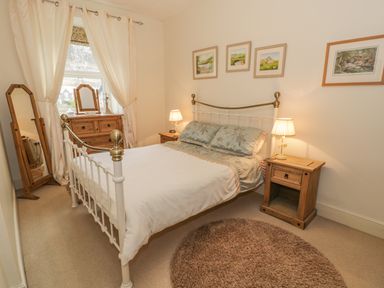 A bedroom with a bed a wooden dresser a standing mirror and framed pictures on the wall at Manod View in Blaenau Ffestiniog